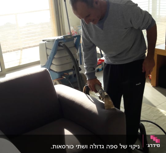 אדם מנקה ספה עם מכשיר ניקוי מקצועי